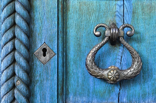 image of weathered door and ornate door knocker and key hole, suggesting home organizer value of possibility and transformation